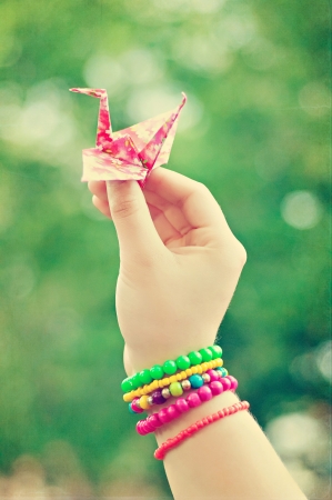 Origami crane in hand with colorful braceletsの写真素材