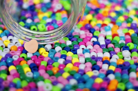 Spilled Jar of colorful beads and heartの写真素材