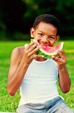 Young boy eating watermelon in fieldの写真素材
