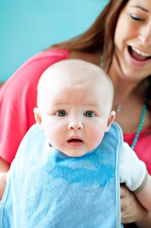 Mom smiling holding baby with shocked scared expressionの写真素材