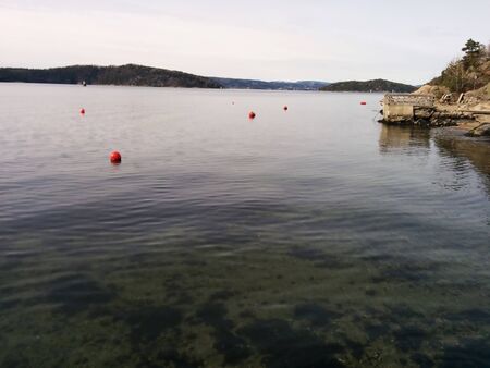 View of the ocean with buoys and a small pierの写真素材