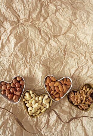 Concept of food designed for Valentine's day. Raw nuts in gift molds in the form of hearts. Healthy eating in eco-friendly packaging. Food photo, top view, vertical orientation, copy spaceの写真素材