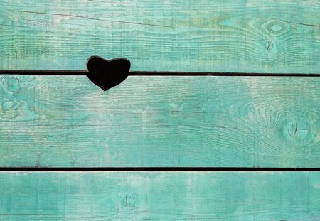 Blue background of old painted wooden boards horizontally assembled with a decorative cut-out hole in the shape of a heart.の写真素材