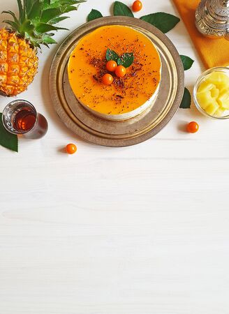Bright yellow pineapple pie on a silver tray with a whole fresh pineapple and a cup of tea with a teapotの写真素材
