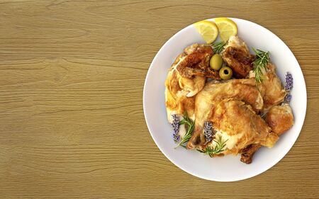 The concept of simple healthy food. White dish with grilled chicken slices with crust with sprigs of herbs, lemon wedges and olives on wooden background. Delicious cooked chicken Food photo, horizontal orientation, copy spaceの写真素材