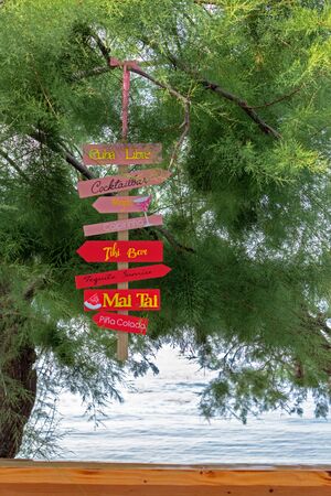 Beach bar, wooden counter with bright signs with signs of alcoholic cocktails overlooking the seaの写真素材
