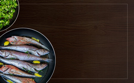 Fresh fish cleaned and prepared for cooking in a frying pan and spinach on a background with frame