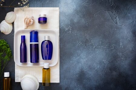 Cosmetic Spa mockup. Blue cosmetic bottles on a white towel with shells on a blue background. Beauty salon, table with creams and towels, top view, copy spaceの写真素材