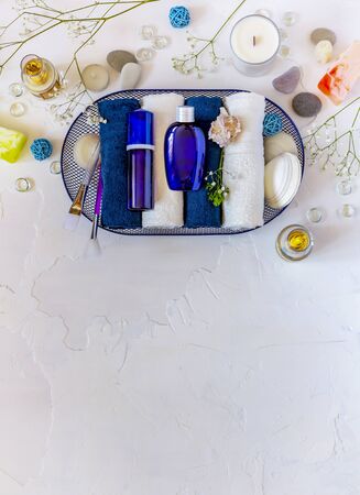 Cosmetic Spa mockup. Place your design. Blue cosmetic bottles on folded towels in a basket with seashells. Beauty salon, table with creams, soap, towels and candles. Vertical orientation, top view, copy spaceの写真素材