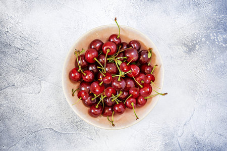 Fresh, ripe, sweet cherry on textural, beautiful plate on blue background. Concept of beauty of...