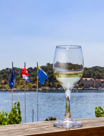 A glass of white wine on the counter of an open restaurant with a view of the seaの写真素材
