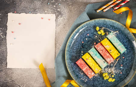 Colorful marshmallows on a blue plate with ribbons, flowers and white sheetの写真素材