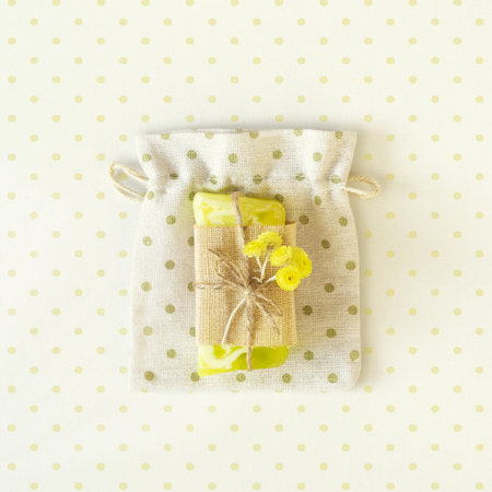 Top view on bar of handmade natural soap or dry shampoo with flowers on on a bag of rustic fabric. Close up of home spa products made from natural ingredients, the best gift and skin careの写真素材