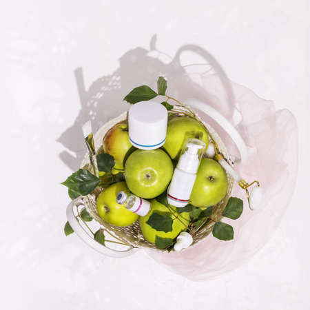 Cosmetic composition with green apples, bottles with cream and beauty accessories on a white background. Healthy, summer, natural cosmetics. Anti-aging treatments for summer seasonの写真素材