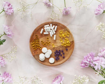 Health care composition with various types of vitamins, dietary supplements and chrysanthemums. Natural remedies that increase immunity. Tablets, capsules, pills and dragees on a floral backgroundの写真素材