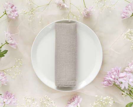 Spring season composition with a white plate with a napkin and flowers on a light pink background. Romantic, table setting with chrysanthemums and gypsophila. Wedding Concept. Top viewの写真素材