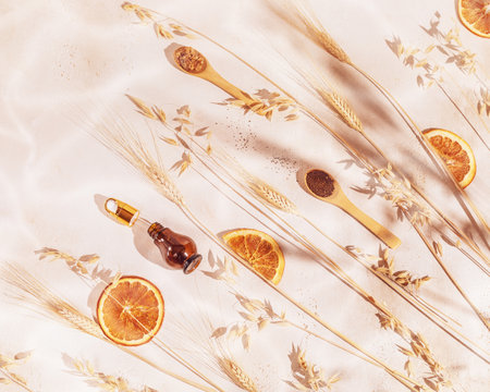 Spa composition with a jar of serum, wooden spoons with natural ingredients for home made scrub, ears of rye and wheat, dried oranges and a bowl. Eco friendly bathroom and spa accessories. Home spaの写真素材