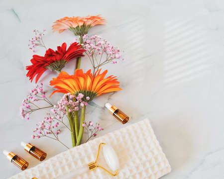 Bouquet of gerberas, bottles of serum and oils and cosmetics accessoriesの写真素材