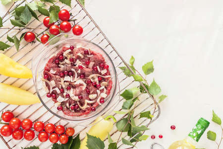 Food composition with beef, new crop seasonal vegetables on a grill, bottle of white wine and birch twigs. Cooking meat with farm vegetables in the open air. The concept of a picnic and healthy foodの写真素材