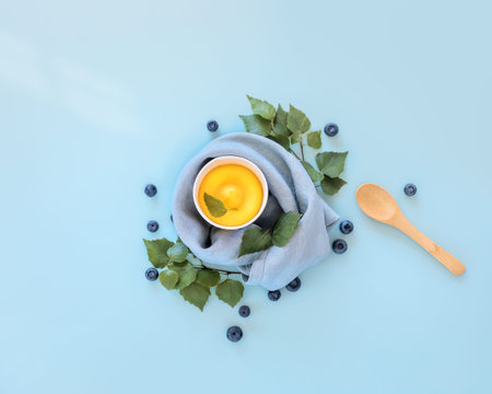 Fruit ice cream, blueberries, lief and a wooden spoon on a blue background