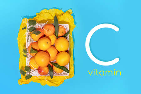 Locally grown, organic, citrus fruits is a nature Vitamin C. Horizontal, summer, sunny, fruits composition with fresh oranges in a white box on a blue background with inspiration vitamin Cの写真素材