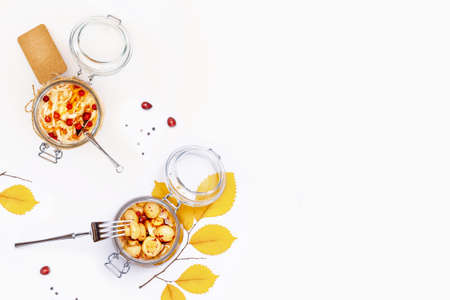 Handmade, vegan food. Fermented organic mushrooms and cabbage with cranberries and spices in a glass jars on a white background with copy space. Autumn composition with jars of fermented foodの写真素材