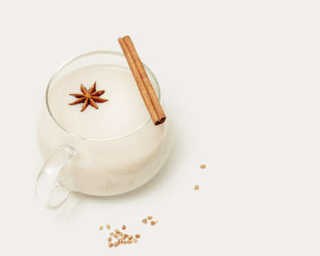 Natural non lactose buckwheat milk. Vegan food composition with glass cup of plant milk with a cinnamon stick and anise on a white table. Vegan healthy milk products. eco friendly food bannerの写真素材