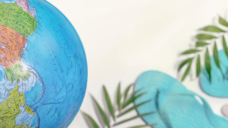 Travel composition with Globe, flip-flop and palm leaves on a white background with copy space suitable for travel agencies. The concept of choosing travel and recreation in exotic distant countriesの写真素材