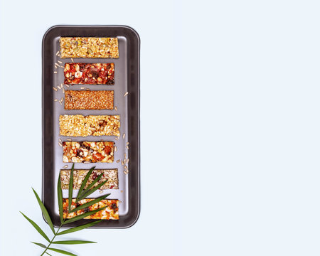Natural granola cereal bars with nuts, seeds, oats, berries and dry fruits on a blue background with...