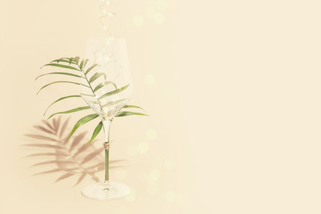 Holiday composition with an empty glass with palm leaf and lightning on a pink background with copy space. Holiday party cardの写真素材