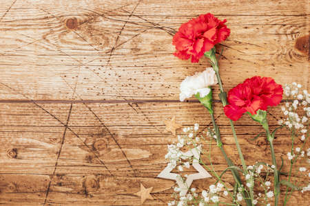 Red and white carnations, gypsophila and decorative stars on a wooden backgroundの写真素材