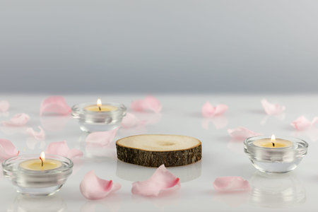 Wooden podium with pink rose petals and candles on a white table. Concept scene stage showcase for new product, promotion sale, banner, presentation, cosmetic. Soft image and soft focus styleの写真素材