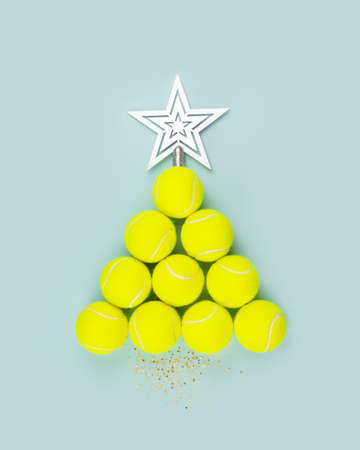 Tennis, winter holidays composition with yellow tennis balls in the form of a New Year Tree with decorative star on a blue background. New year card for a tennis competition or tennis equipment saleの写真素材