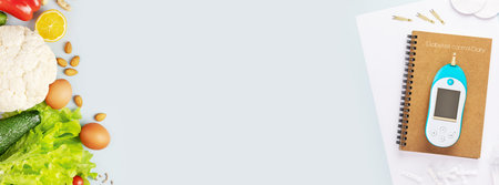 Diabetic control and diet banner with glucose meter, test strips for determining blood sugar levels, lancets, diary of diabetes control and natural keto products on a blue background with copy spaceの写真素材