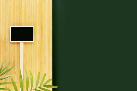 Eco friendly, natural background. Empty dark green table and wooden kitchen board with palm leaves...