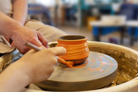 The Potter with student coloring a pot from clay on a Potter's wheel at workshop. Teaching pottery on a potter's wheel. Hobbies, craft and handwork. Healthy free time for children. selective focusの写真素材