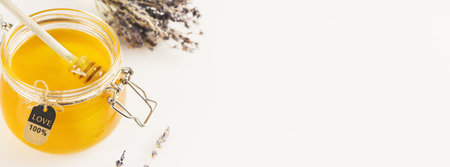 Food banner with natural liquid honey in glass jar with lavender flowers on a white background and copy space. Honey is a natural, folk medicine. Immune boosting food. Soft image and soft focus styleの写真素材