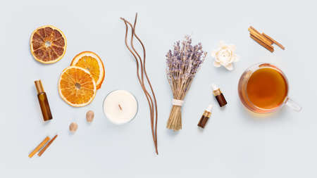 Relax at home. Cup of herbal tea, aroma candle, sticks, lavender flowers, dry orange slices and natural oils on a blue background. Insomnia or depression treatment. self care and me time conceptの写真素材