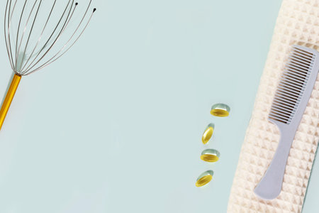 Comb on a white towel, massager for head and vitamin capsulesの写真素材