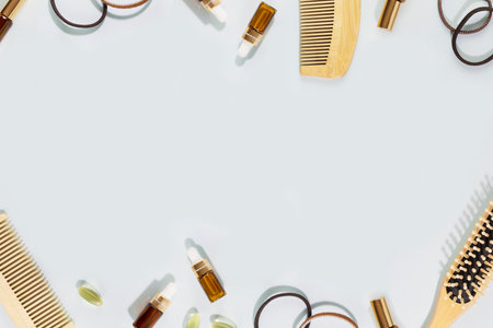 Hair care flat lay with wooden combs, vitamins for health hair, natural oils, accessories and eucalyptus leaves on a blue background with copy space. Natural beauty products for hairの写真素材