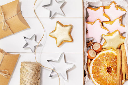Hande made presents with home made cookies, dry fruits, nuts and cinnamon stiks on a white wooden background. Winter holiday pastries. Christmas cookies. Hand made gifts. Flat layの写真素材