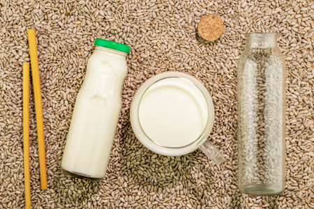 Sunflower seed milk in glass cup and bottles on background with sunflower seedの写真素材