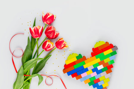 Holiday card with bouquet with red tulips and hande made bricks heart. Spring flowers on blue background. Greeting card for Valentine's Day, Woman's Day and Mother's Day holidays. Gift for motherの写真素材