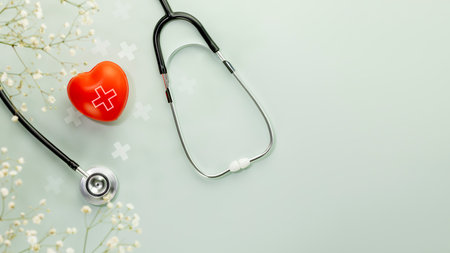 Red heart love shape hand exercise ball with stethoscope on blue background with flowers. Health care, organ donation, love and family insurance concept, world heart day. Flat lay, copy spaceの写真素材