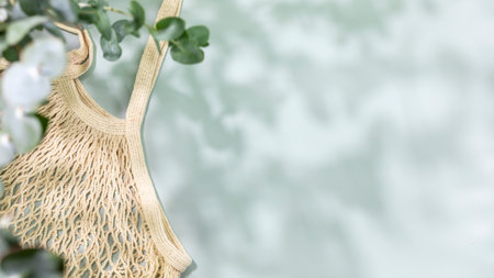 Eco friendly shopping concept. Environment, sustainable composition with natural textile bag on blue background with green leaves and shadows. Flat lay, copy spaceの写真素材