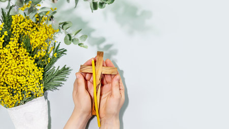 Womans hands hold crucifixion and candles on blue background with copy spaceの写真素材