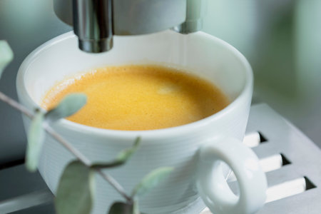Close-up of fresh hot espresso pouring from coffee machine. Professional coffee brewing. Cup of...