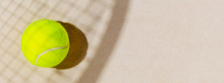 Tennis banner with tennis yellow ball on the sand beach with racket shadow. Tennis competitions, healthy sport and outdoor activities concept. Flat lay, banner size, copy spaceの写真素材