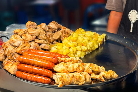 Vibrant street food scene with grilled sausages, chunks of chicken, and diced potatoes cooking on...