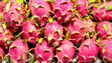 Fruit backdrop with vibrant pink dragon fruit stacked at a market, highlighting the fruit's role in wellness trends due to its antioxidant properties and appeal in visually driven food marketsの写真素材
